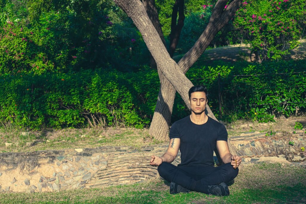 Man meditating peacefully in a lush Jaipur garden, embracing wellness and relaxation.